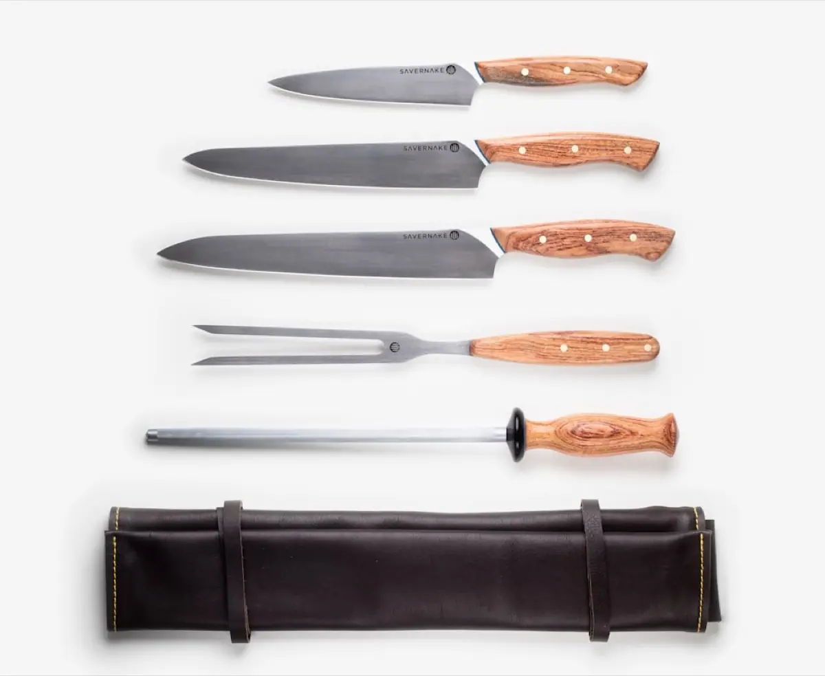 A set of wood-handled chef knives with a leather roll