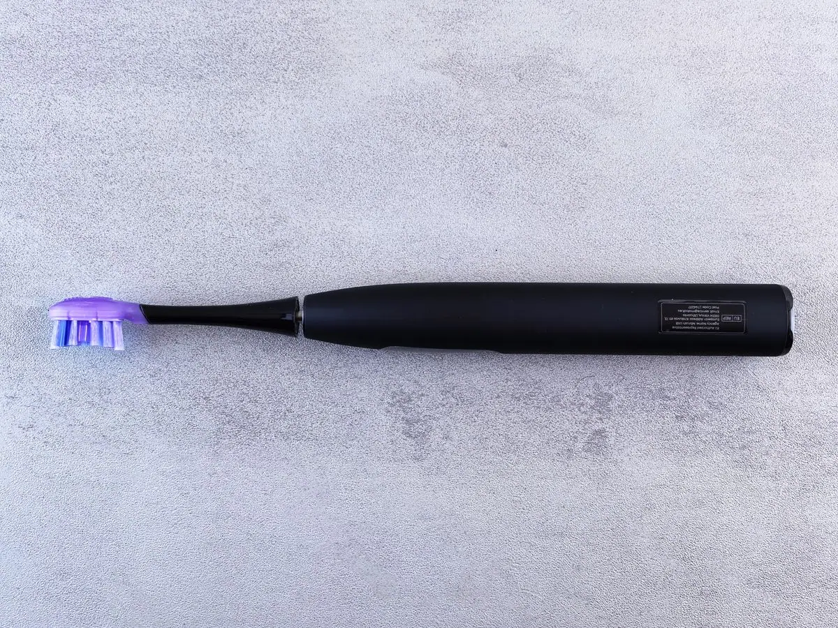A black electric toothbrush on a surface