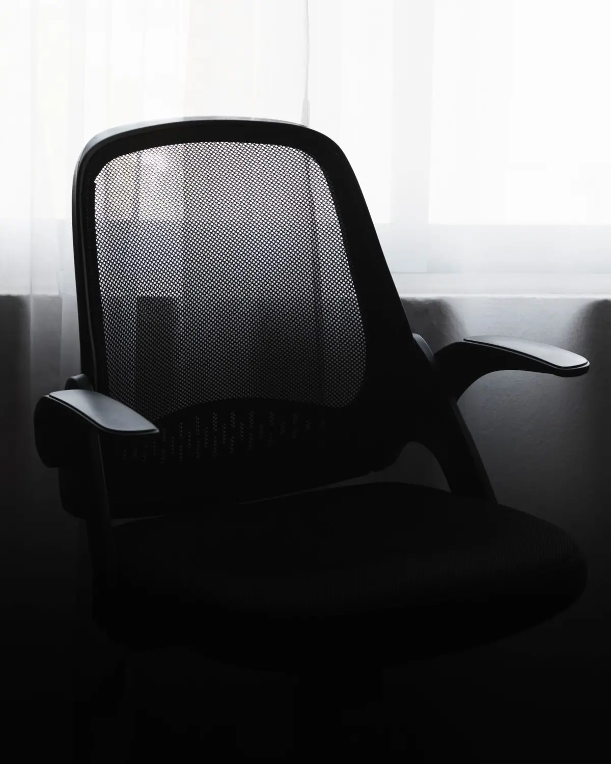 A black mesh ergonomic office chair by a window