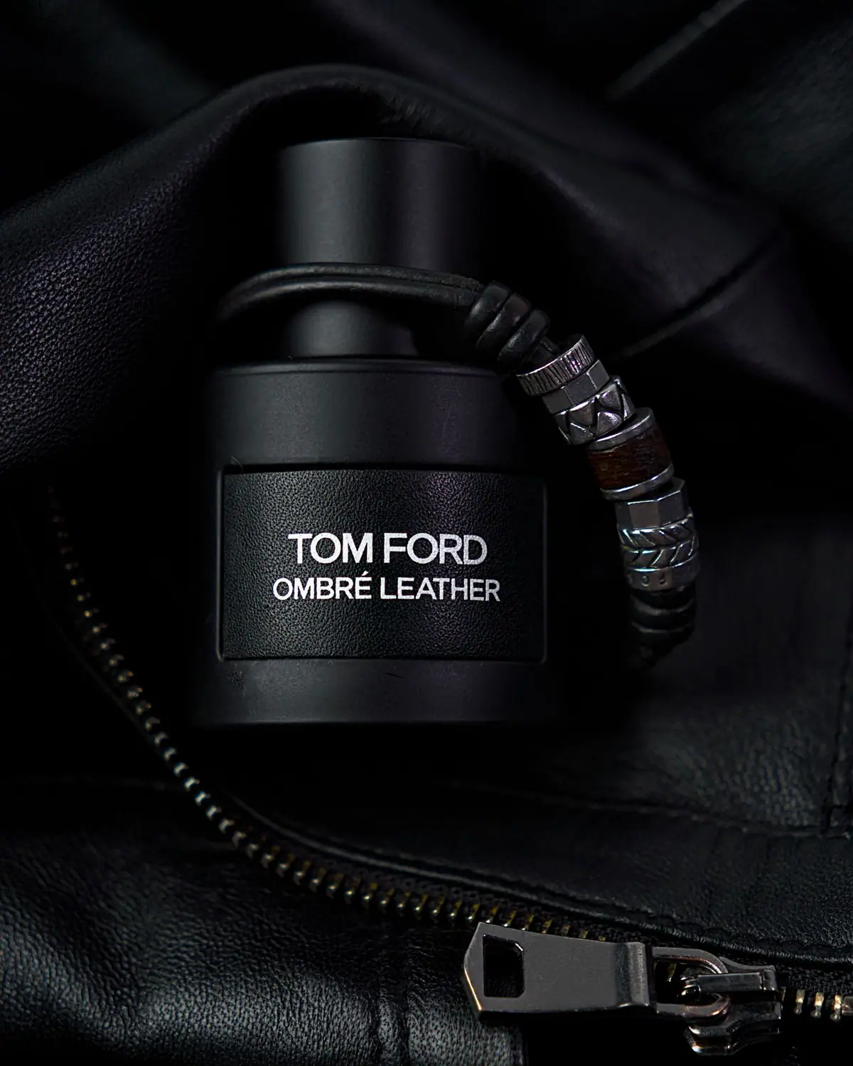 A men's luxury fragrance bottle on black leather