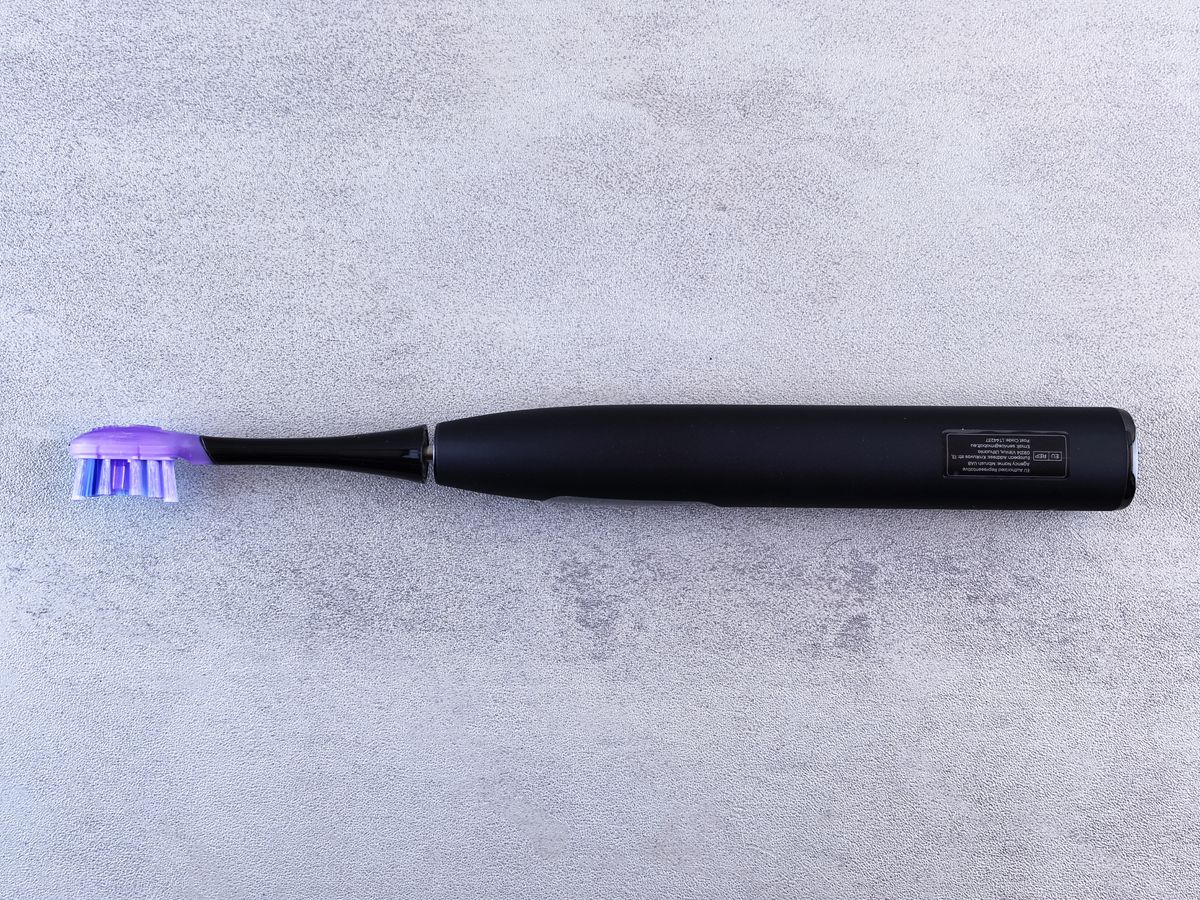 A black electric toothbrush on a surface
