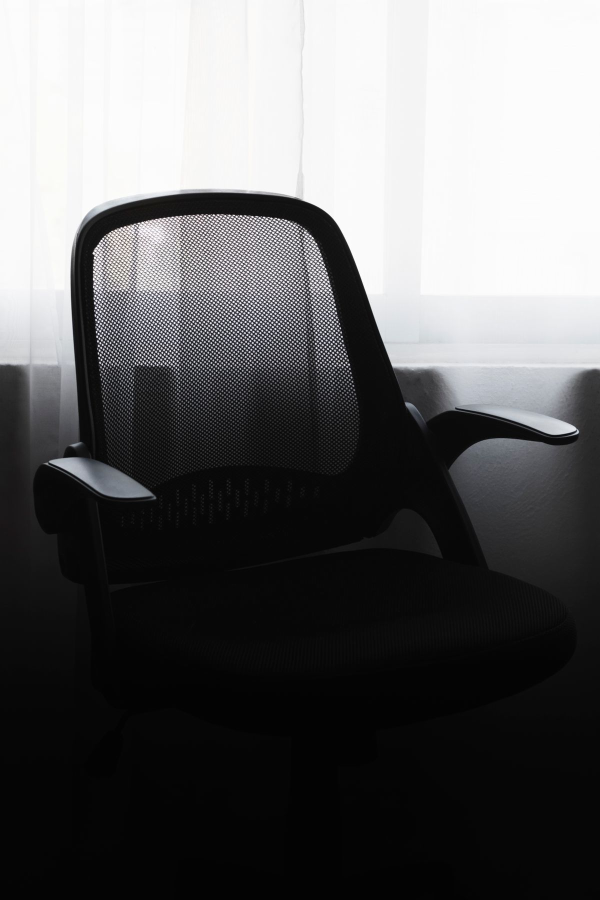 A black mesh ergonomic office chair by a window