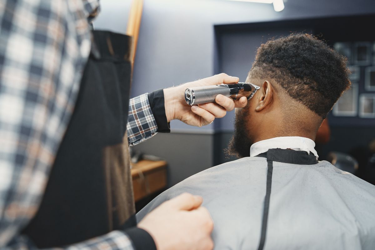 A barber cutting a man's hair with clippers