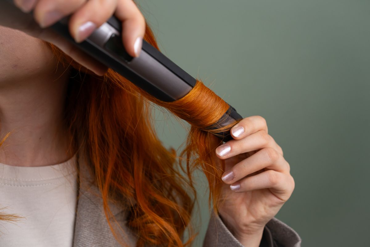 A woman curling her hair with a curling iron
