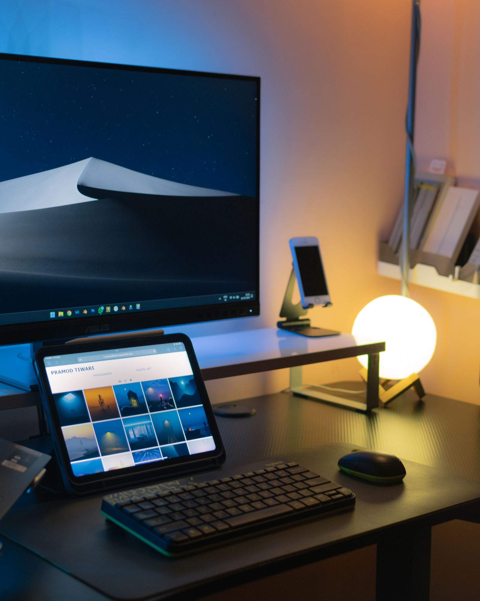 A modern desk with tech gadgets and a glowing lamp