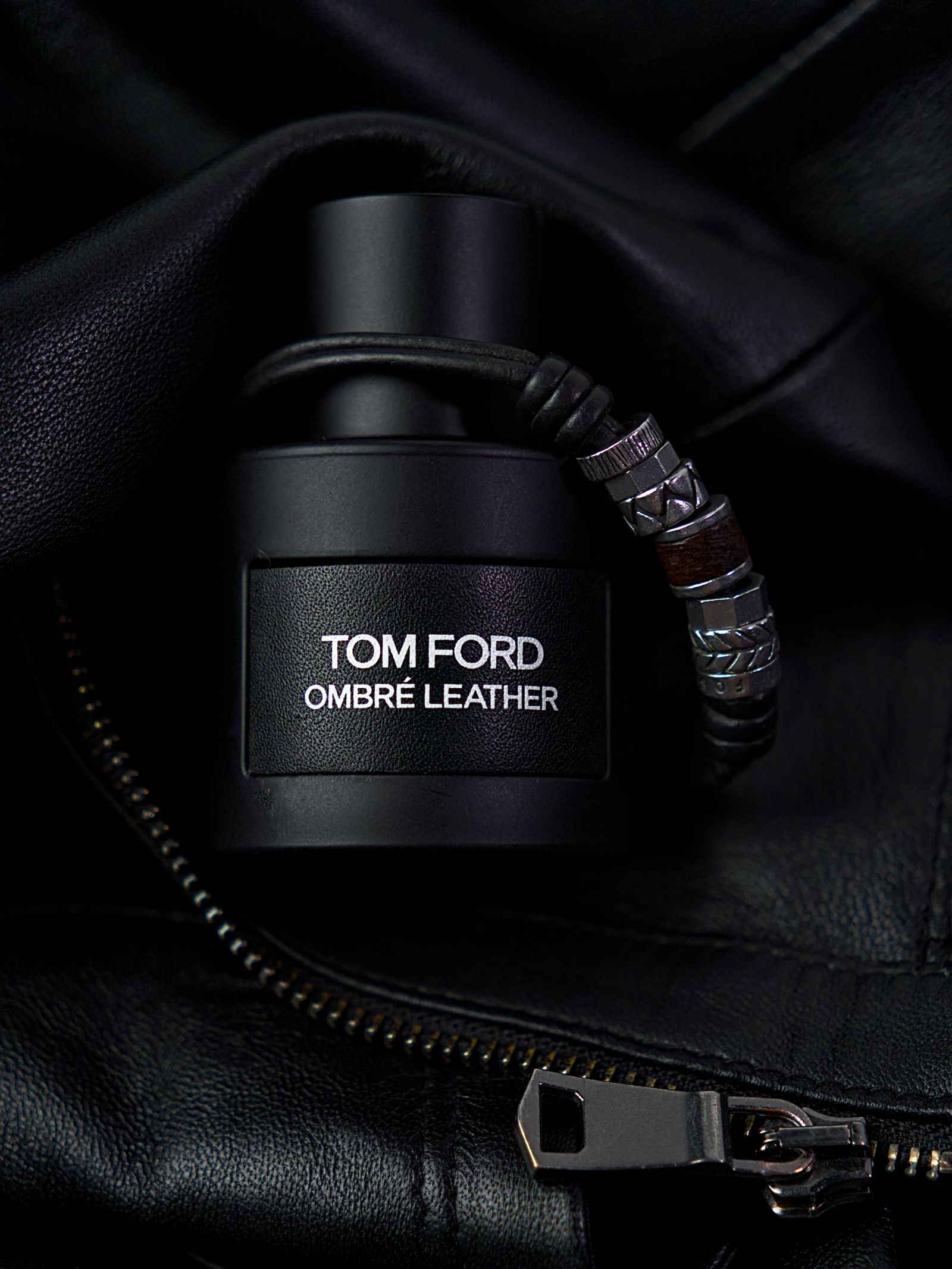 A men's luxury fragrance bottle on black leather